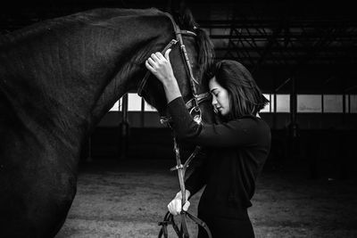 Full length of a young woman standing in stable