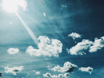 Low angle view of sunlight streaming through clouds