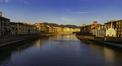 Bridge over river by buildings in city against sky