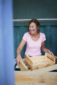 Happy senior gardener with wooden crates sitting at yard