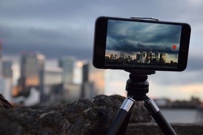 Close-up of camera against cloudy sky