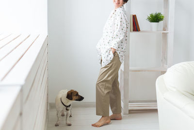 Woman with dog standing at home