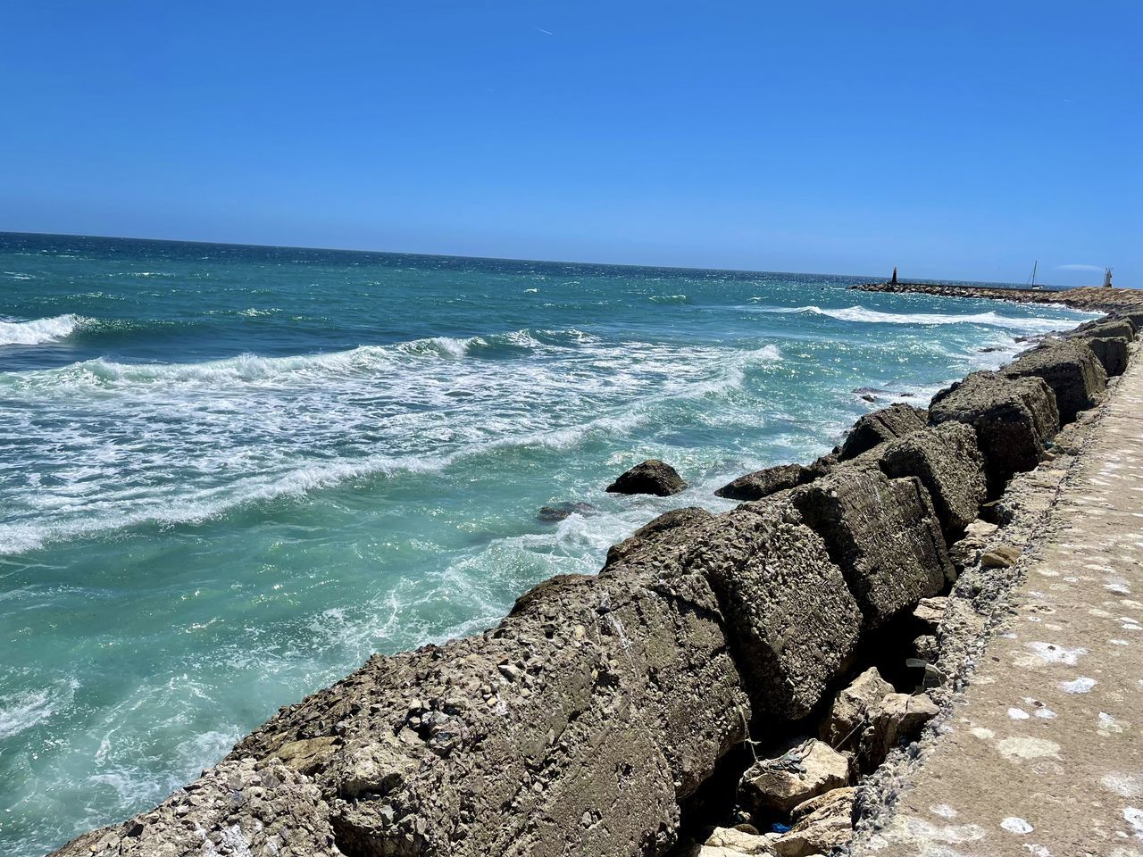 sea, water, land, beach, sky, shore, body of water, wave, ocean, scenics - nature, beauty in nature, nature, coast, horizon, rock, horizon over water, wind wave, vacation, clear sky, motion, terrain, cliff, day, blue, tranquility, tranquil scene, no people, travel destinations, sunny, sunlight, outdoors, water sports, sports, sand, cove, idyllic, coastline, travel, bay, breakwater, tourism, holiday