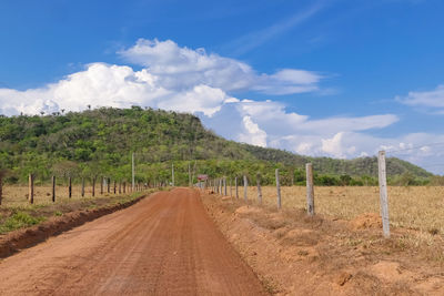 Road amidst field against sky