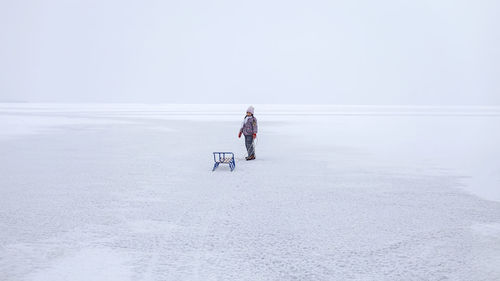 Man on snow covered land against sky