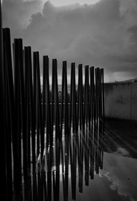Wooden fence by lake against sky
