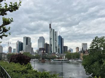 City at waterfront against cloudy sky