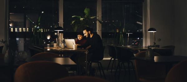 Confident male and female professionals working late together at creative office