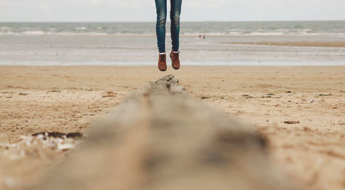 Low section of woman jumping on beach