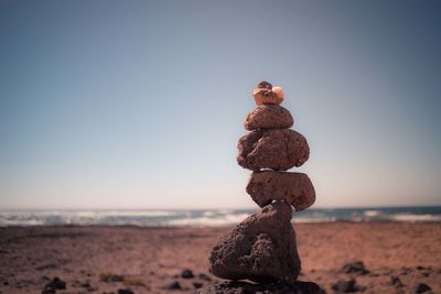 Stack of pebbles on beach against clear sky