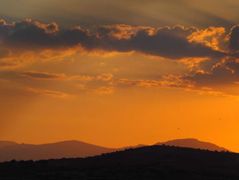 Scenic view of silhouette mountains against orange sky