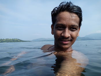 Close-up of shirtless man swimming in river against sky