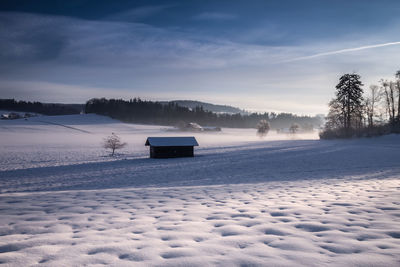 Scenic view of snow covered field against sky