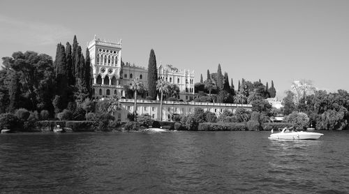 View of buildings by river against clear sky