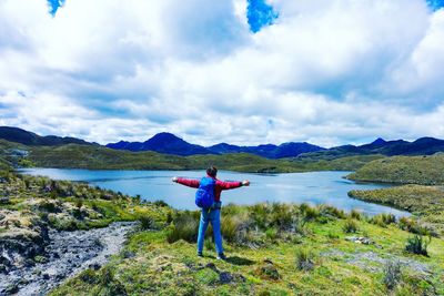 Rear view of man standing on lake against sky