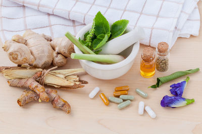 High angle view of herbs in spices with capsules on table