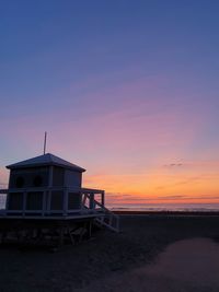 Built structure on beach against sky during sunset