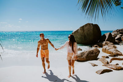 Smiling couple walking while holding hands at beach