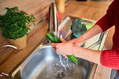 Closeup of a woman's hands washing vegetables under running tap water in the kitchen. cooking.