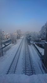 Snow covered railroad tracks against sky during winter