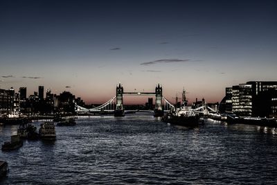 Bridge over river in city against sky during sunset