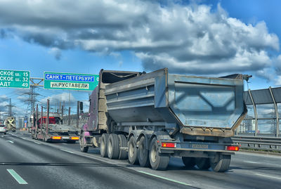 Vehicles on road against cloudy sky