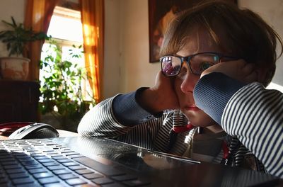 Close-up of boy using laptop at home