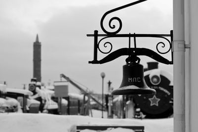 Bell mounted on wall against sky during winter