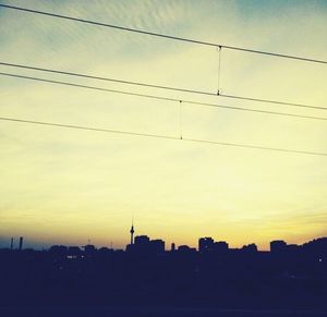 Low angle view of silhouette electricity pylon against sky during sunset