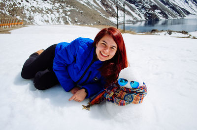 Young woman sitting on snow covered field