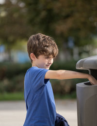 Caucasian kid 9 year old throwing trash in public trashcan. concept of garbage, recycle environment