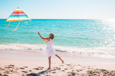 Boy standing on beach against sky