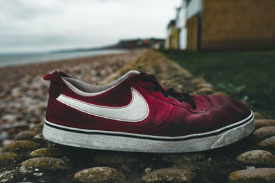 Close-up of shoes on beach against sky