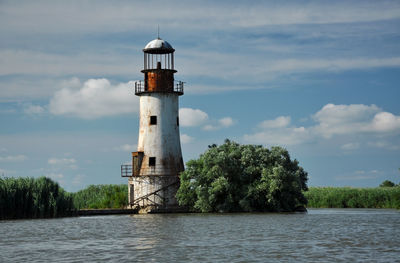 Lighthouse by lake against sky