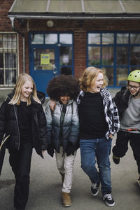 Playful multiracial friends walking while leaving from school