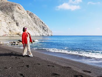 Woman standing at beach against sky