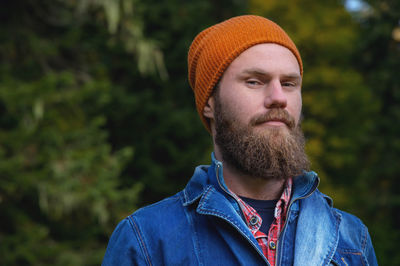 Portrait of a young hipster in a hat posing on the street. smiling bearded man in the forest