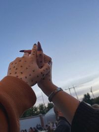 Close-up of woman hand against sky
