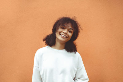 Portrait of teenager girl standing against wall