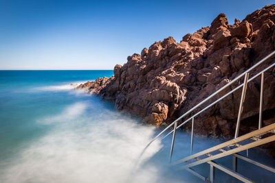 Rock formation by sea against sky