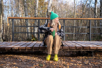 Rear view of woman sitting on railing