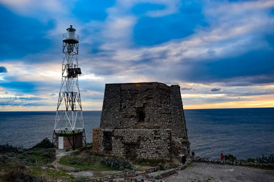 Lighthouse by sea against sky