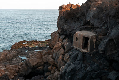 Rock formation on beach against sky