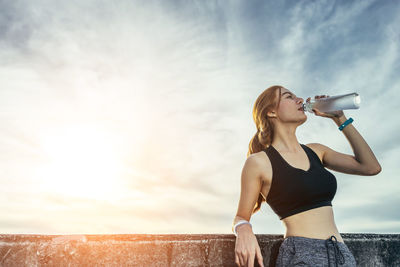 Woman standing by bottle against sky