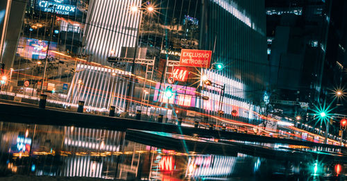 Illuminated buildings by street in city at night