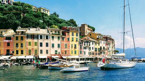 Sailboats moored on sea against buildings in city