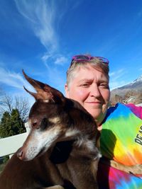 Close-up of smiling woman with dog against sky