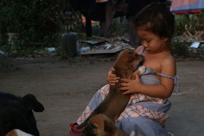 Cute girl playing with dog on footpath