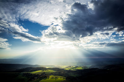 Sunbeams streaming through clouds over landscape