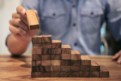 Midsection of man stacking wooden blocks on table